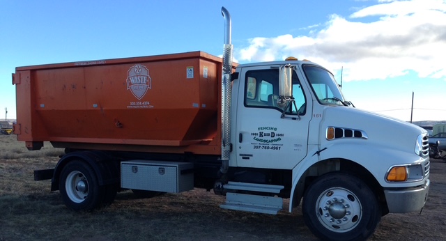 K BAR D truck hauling an orange roll-off dumpster