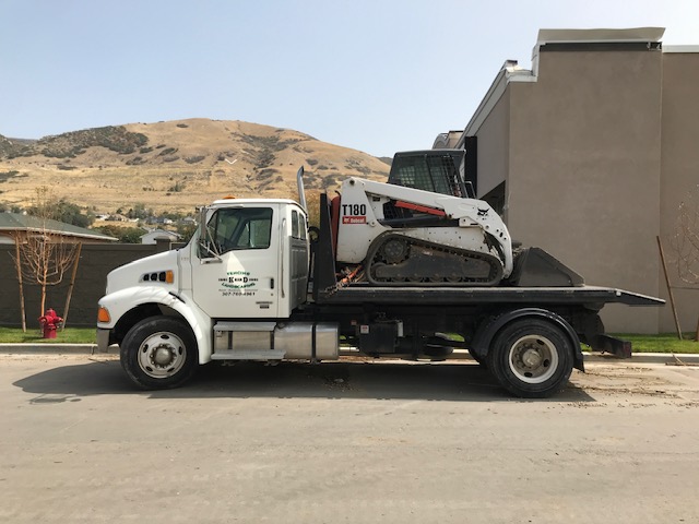 Truck hauling skid steer for demolition work