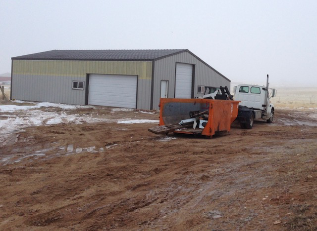 Demolition site with roll-off container and truck